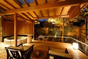 伊豆之国市Yumeguri no Yado Yoshiharu的庭院设有带椅子的木制甲板和热水浴池。