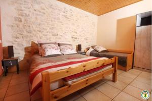 Saint-Martin-en-VercorsGîte La Morandière的一间卧室设有一张木床和石墙