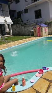 康赛瓦托利亚Pousada Pedacinho do Céu的坐在游泳池冲浪板上的一个小女孩