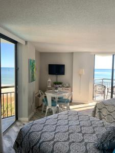 默特尔比奇426 Belle Vue Magnificent Oceanfront studio with two balconies的一间卧室设有一张床铺和一张桌子,享有海景