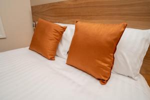 卢顿Eagle Hotel Luton Airport的床上有两个橙色枕头