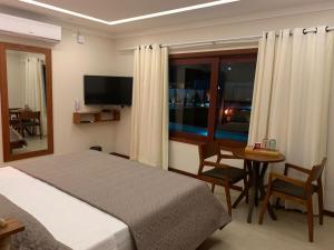圣米格尔-杜戈斯托苏AWARA POUSADA BOUTIQUE的一间卧室配有一张床、一张桌子和一台电视