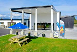 霍基蒂卡Hokitika's Kiwi Holiday Park and Motels的大楼前带蓝伞的野餐桌