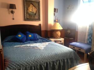 圣地亚哥拉卡斯特拉纳酒店的一间卧室配有一张带蓝色床单和一盏灯的床。