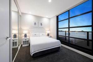 墨尔本The Hamptons Apartments - St Kilda的卧室设有白色的床和大窗户