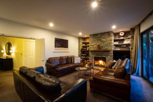 瓦纳卡酸橙树山林小屋的客厅配有真皮沙发和壁炉
