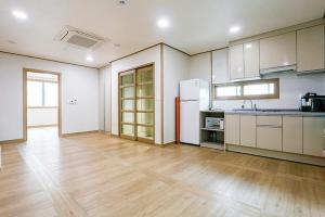济州市济州特别旅馆的一间铺有木地板的大厨房,配有白色的橱柜