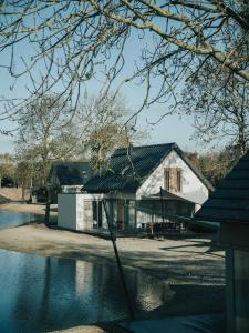 奥德多普Ridderstee Ouddorp Duin的湖畔的白色房子,有黑色的屋顶