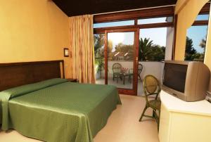 斯塔加托卡罗港度假酒店的一间卧室设有一张床、一台电视和一个阳台。