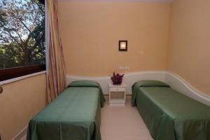 斯塔加托卡罗港度假酒店的带窗户的客房内的两张床