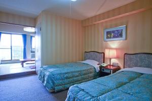 Ōtakiホテル グリーンヒル 大多喜的酒店客房设有两张床和窗户。