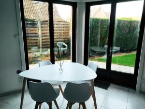 隆普雷Maison familiale tout confort avec garage的窗户客房内的白色桌椅