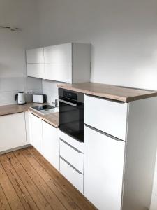 瓦尔内明德Ferienapartment Warnemünde 2的厨房铺有木地板,配有白色橱柜。