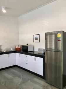 宋卡Ban Soi San Sook Homestay的厨房配有不锈钢冰箱和微波炉。