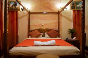 MweigaSangare Gardens的一间卧室配有一张带橙色毯子的大床