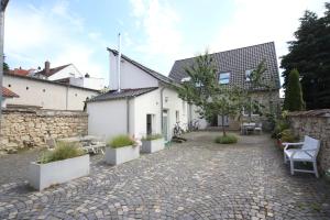 美因茨Hofhaus mit Riesengarten - gemütliches Häuschen im Kern des schönsten Mainzer Stadtteils Finthen的白色建筑的庭院,有盆栽植物