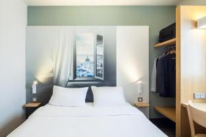 奥尔日河畔圣米歇尔B&B HOTEL Saint-Michel sur Orge的卧室设有一张白色大床和一扇窗户。
