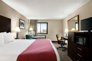 苏福尔斯Baymont by Wyndham Sioux Falls North,I-29,Russell St, Airport的配有一张床和一台平面电视的酒店客房