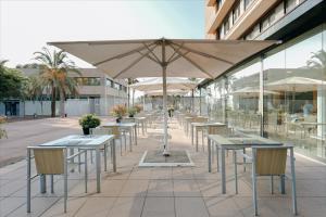 巴塞罗那Hesperia Barcelona Del Mar的一排桌椅和一把伞