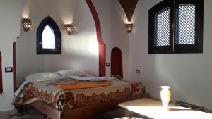 卢克索Leyla Eco Resort Queen Suites的一间卧室配有一张桌子和两个窗户。