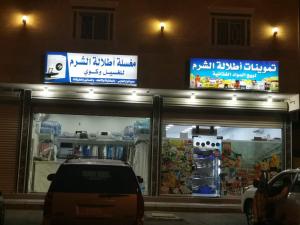 延布Etlalet Al-Sharm Apartments的夜间停在商店前面的汽车
