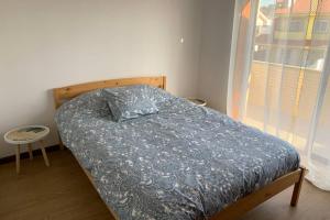 孔迪镇Carminho beach house的一间卧室配有一张带蓝色棉被的床和窗户。