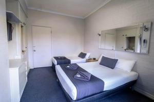 布里斯班金斯福德河畔酒店的酒店客房,设有两张床和镜子