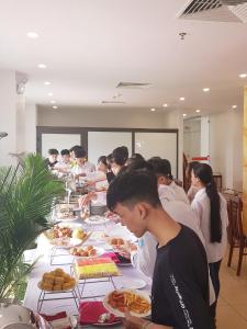 清化Long Anh Hotel的一群人站在长桌旁吃着食物