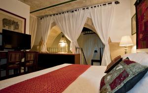 莱切Dei Due Portoni Suite Storica的一间卧室配有一张带窗帘的床和电视。