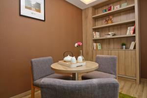 西安西安大寨路亚朵酒店的客厅设有两把椅子、一张桌子和书架