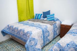 JuayúaMixtepek的一间卧室配有两张带蓝白色床单的床