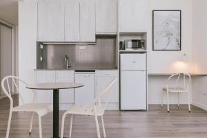 圣库加特德尔瓦勒斯CIM Aparthotel的厨房配有白色橱柜和桌椅