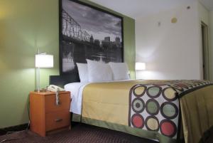 新坎伯兰Super 8 by Wyndham New Cumberland的酒店客房的墙上设有一张带照片的床。