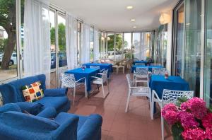 里米尼Hotel Cheri的餐厅设有蓝色的桌椅和窗户。