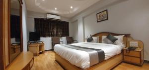 拉杰果德JMC集团酒店的一间卧室配有一张大床和电视