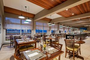 弗洛里亚诺波利斯Slaviero Baia Norte Florianópolis的餐厅设有木桌、椅子和窗户。