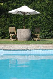 阿马马尔圣米格尔杜罗旅馆的游泳池畔的一把遮阳伞和两把椅子