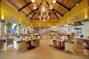 沙努尔尹娜圣德海滨酒店的一间带桌椅和吊灯的餐厅