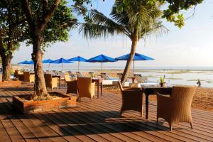 沙努尔尹娜圣德海滨酒店的海滩上的餐厅,配有椅子和遮阳伞