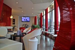沙勒维尔-梅济耶尔基里亚德查尔勒维勒梅兹尔酒店的餐厅设有白色椅子和墙上的电视