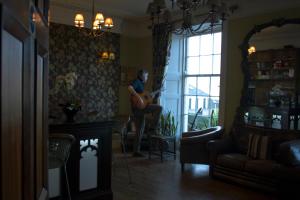 法尔茅斯The Grove Falmouth的女人在客厅里弹吉他