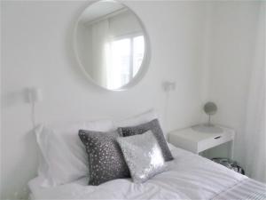 奥卢Compact high quality top floor studio in perfect location的卧室配有一张带镜子的白色床