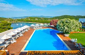 考考纳里斯斯基亚索斯岛宫殿酒店的一个带椅子和遮阳伞的室外游泳池