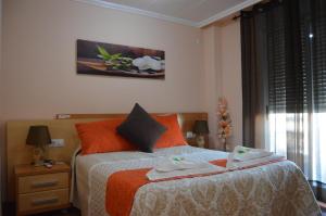 埃尔达Hostal Carrizo的一间卧室配有带橙色枕头的床