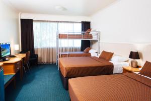 汤斯维尔城市绿洲酒店的酒店客房设有两张双层床和一张书桌。