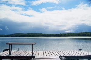 RentynyLetnisko Zalesie的坐在湖面上的一个甲板上的野餐桌