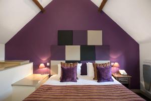 班伯里德丁顿阿姆斯酒店的一间卧室设有一张紫色墙壁的大床