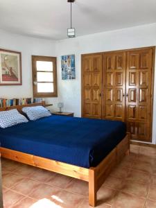 卡隆赫Vila Zara的一间卧室配有一张蓝色的床和木制橱柜。