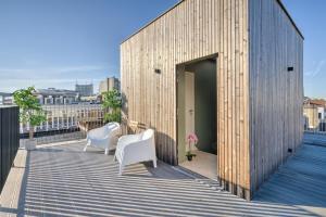 安特卫普Apartment with Rooftop Terrace in the Heart of Antwerp的一座木制建筑,阳台上配有两把白色椅子