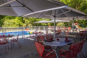 蒙沙南齐利亚蒙沙南勒克鲁佐酒店的一组桌椅,在游泳池旁边配有遮阳伞